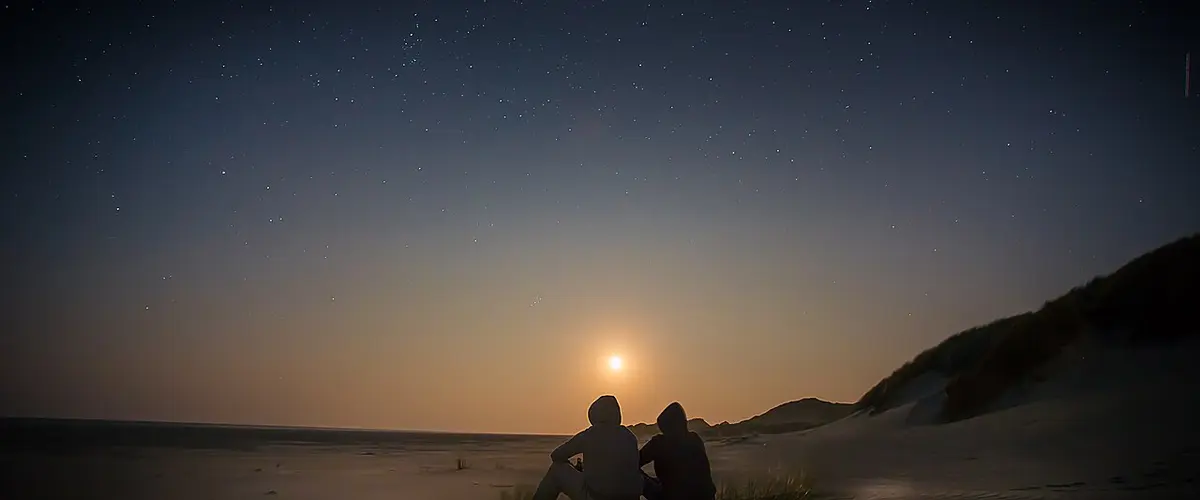 Couple sitting watching sunset (Unsplash)